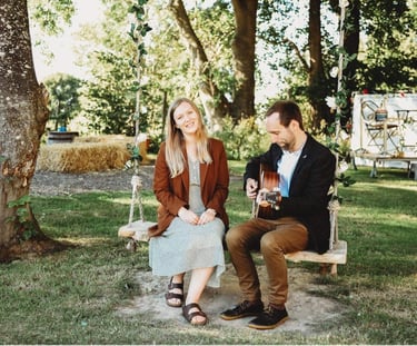 a man and woman sitting on a swing with a guitar at wedding