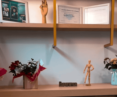 Prateleira com certificados, diplomas e quadros que comprovam a qualificação e formação da profissional da Clínica Lanna Mora