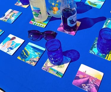 Dessous de verres paysages de Provence Realisart sur une nappe bleue.