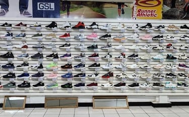 Amplia selección de zapatillas deportivas y calzado para correr exhibidos en la pared de una tienda.