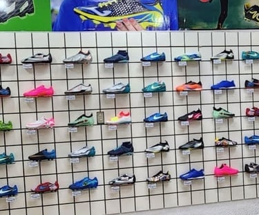 Una exhibición de pared con coloridos botines de fútbol y botas de fútbol en una tienda.