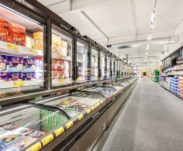 A wide grocery store aisle featuring a long row of glass-door ice cream freezers and frozen food displays.