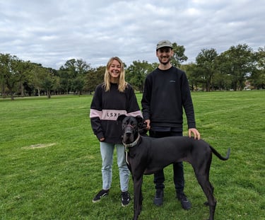 Great Dane and owners in park, smiling after successful training