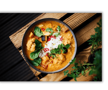 a bowl of food with a wooden table and a potted plant