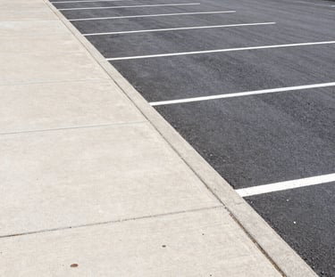 Freshly paved commercial driveway bordered by neatly trimmed landscaping.