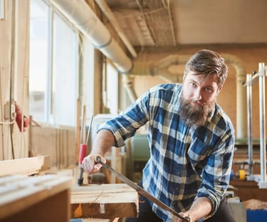 Person using a drawknife to remove the edge of a piece of timber. 