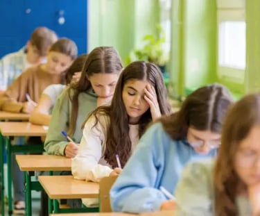 jeunes installés dans une salle, qui passent un examen écrit 