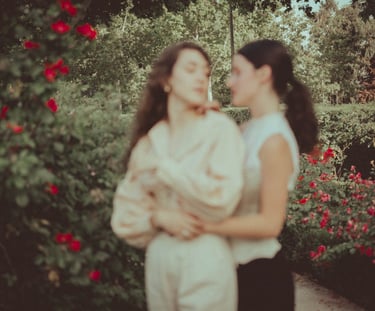 "Pareja lesbiana en el jardín con rosas, foto romántica y desenfocada celebrando su amor en una boda gay."