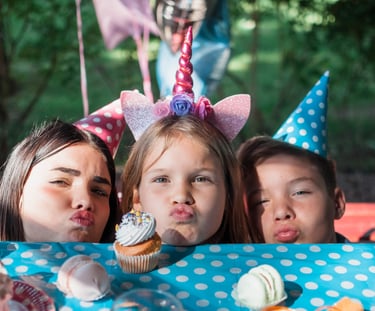three girls with birthday hats on a table