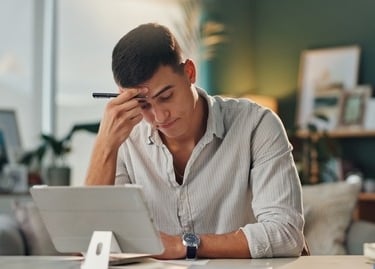 a man sitting at a desk with a laptop and a pen