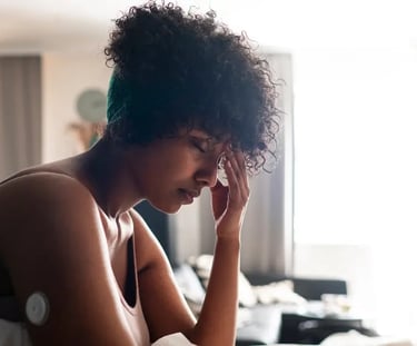 Une femme assise sur un canapé, la tête entre les mains, montrant un moment de désespoir ou de fatigue intense.