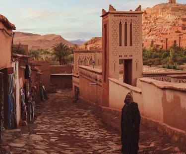 Alleyway in Ait Benhaddou with terracotta walls, man in traditional Moroccan dress in foreground