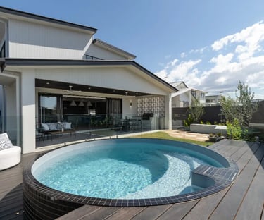 Round plunge pool with pale aqua water and dark charcoal mosaic tiles