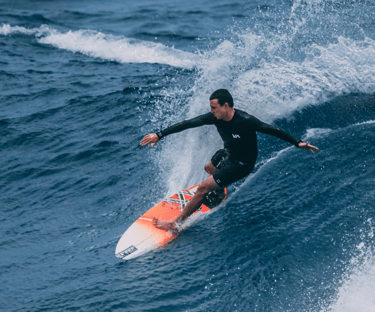 a man in a wetsuit surfing on a surfboard