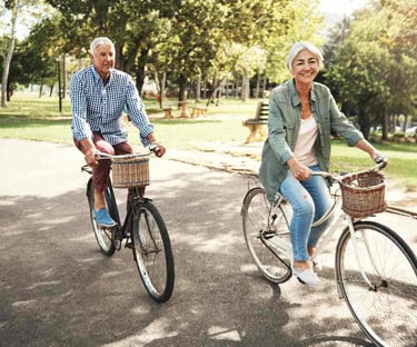 Older woman and man ride bicycles next to park after treatment with acupuncture for pain