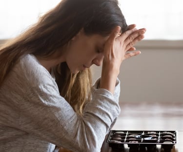 Stressed woman struggling with emotional eating while looking at a box of chocolates.