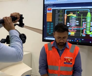 a man in a blue shirt and a camera shooting another man wearing glasses and aditya birla hindalco