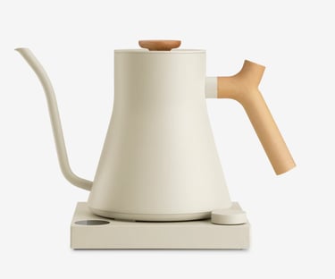 Off-white electric gooseneck kettle with wooden handle on a matching minimalist heating base.