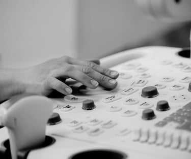 Ultrasonographer with hand on machine keyboard, operating controls.