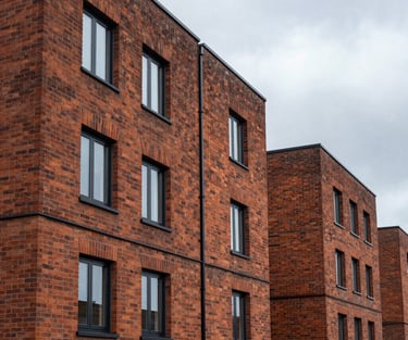 Clinical straight-on shot of a modern brick residential development in Birmingham under overcast West Midlands skies, crisp mortar lines, sharp architectural angles.