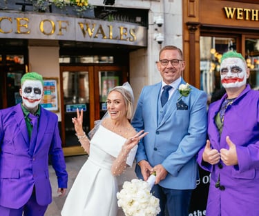 Bride and groom outside Prince of Wales Cardiff, joined by two guests dressed as the Joker in purple suits and face paint.