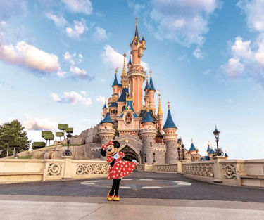 castillo disneyland paris con minnie mouse posando justo al frente