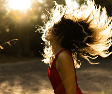 Woman in red dress tosses her long hair back dancing after acupuncture in Carbondale, CO