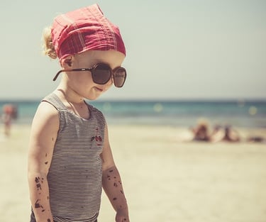 petite fille à la plage avec protection solaire et lunette