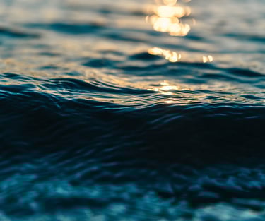 Un gros plan d'une vague au milieu de l'océan avec un reflet de soleil.