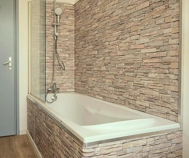 Salle de bain moderne avec baignoire et carrelage effet pierre naturelle.