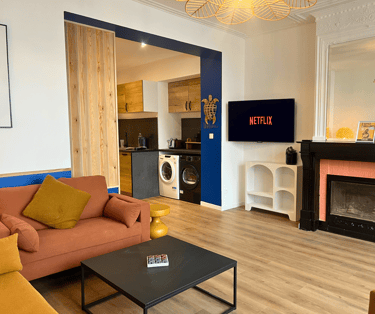 Séjour lumineux avec TV et cuisine équipée dans logement meublé pour pros.