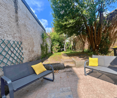 Jardin extérieur avec bancs et verdure, idéal pour se détendre en groupe.