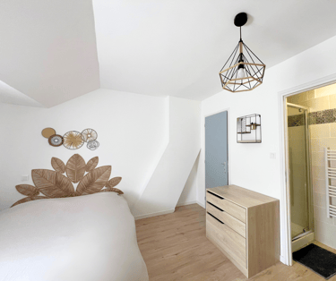 Chambre cosy avec lit double, déco murale et accès salle de bain privative.