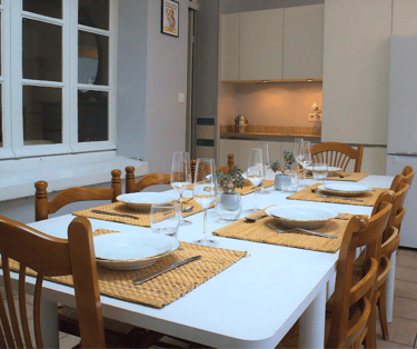Salle à manger conviviale avec grande table dressée dans appartement équipé.