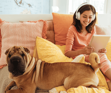 a woman sitting on a bed with a dog and a laptop