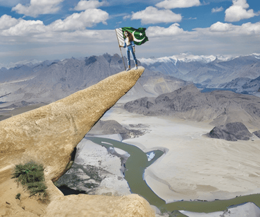 Girl standing at marsur rock skardu with Pakistani flag