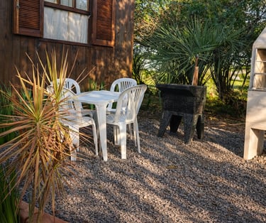 Área de lazer externa da cabana com churrasqueira, tanque e mesa.