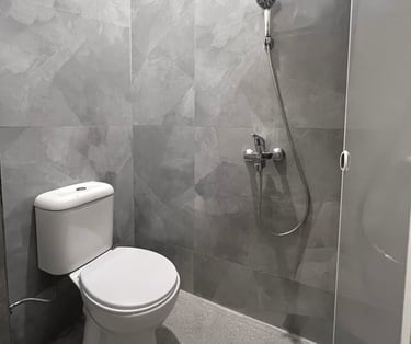 Kamar mandi dalam di Kos Si Bos dilengkapi toilet duduk modern, wastafel, desain bersih minimalis