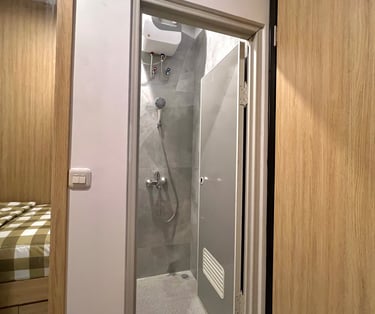 Kamar mandi dalam di Kos Si Bos Surabaya dengan shower modern, dinding keramik, fasilitas premium