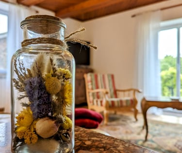 un pot de fleurs séchées dans un bocal, le salon en arrière plan