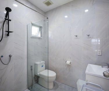 Bright marble-style bathroom with a walk-in shower and window.
