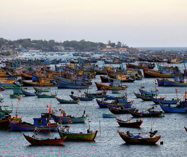 Hundreds of teal and blue wooden fishing boats anchored in the Mui Ne fishing village harbor during