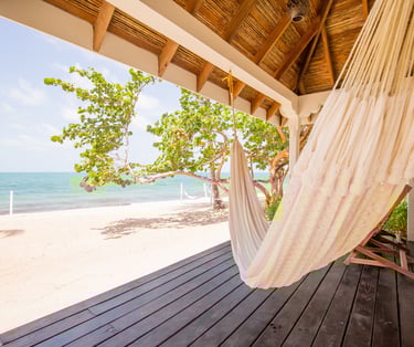 a hammock hanging from a porch over looking Belize beach