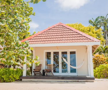 a small white house on the beach in Belize with a hammock