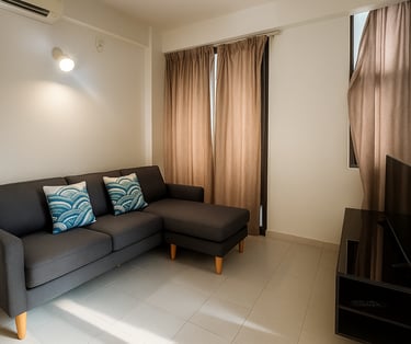 Modern living room featuring a dark grey sectional sofa with blue patterned pillows and a flat screen TV.