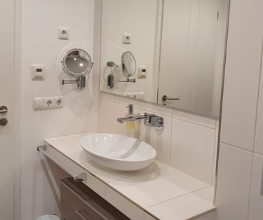 Das Bad mit Waschbecken, Schrank und Kosmetikspiegel