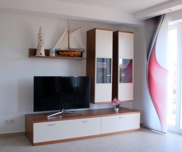 Wohnwand und Flachbild-TV: Dekoriert mit Leuchtturm, Segelboot und Kerze