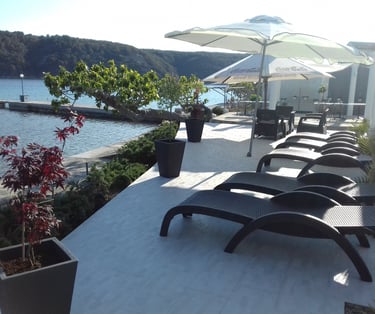 Sonnenliegen mit Sonnenschirmen auf einer Terrasse bei einem Luxusapartment in Kampor auf Rab