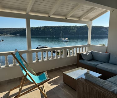 a couch and chair on a porch with a view of the water