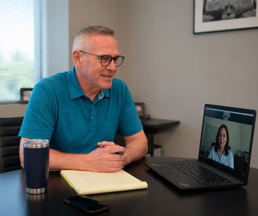 Doug having a professional video conference call on his laptop in a modern office.